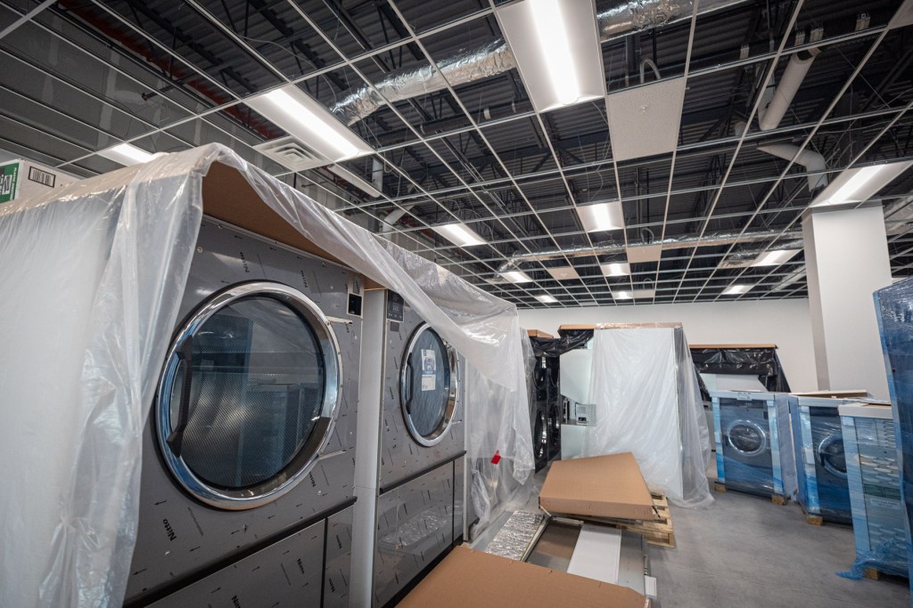 New washing machines are covered in tarps and plastic as they await installation.