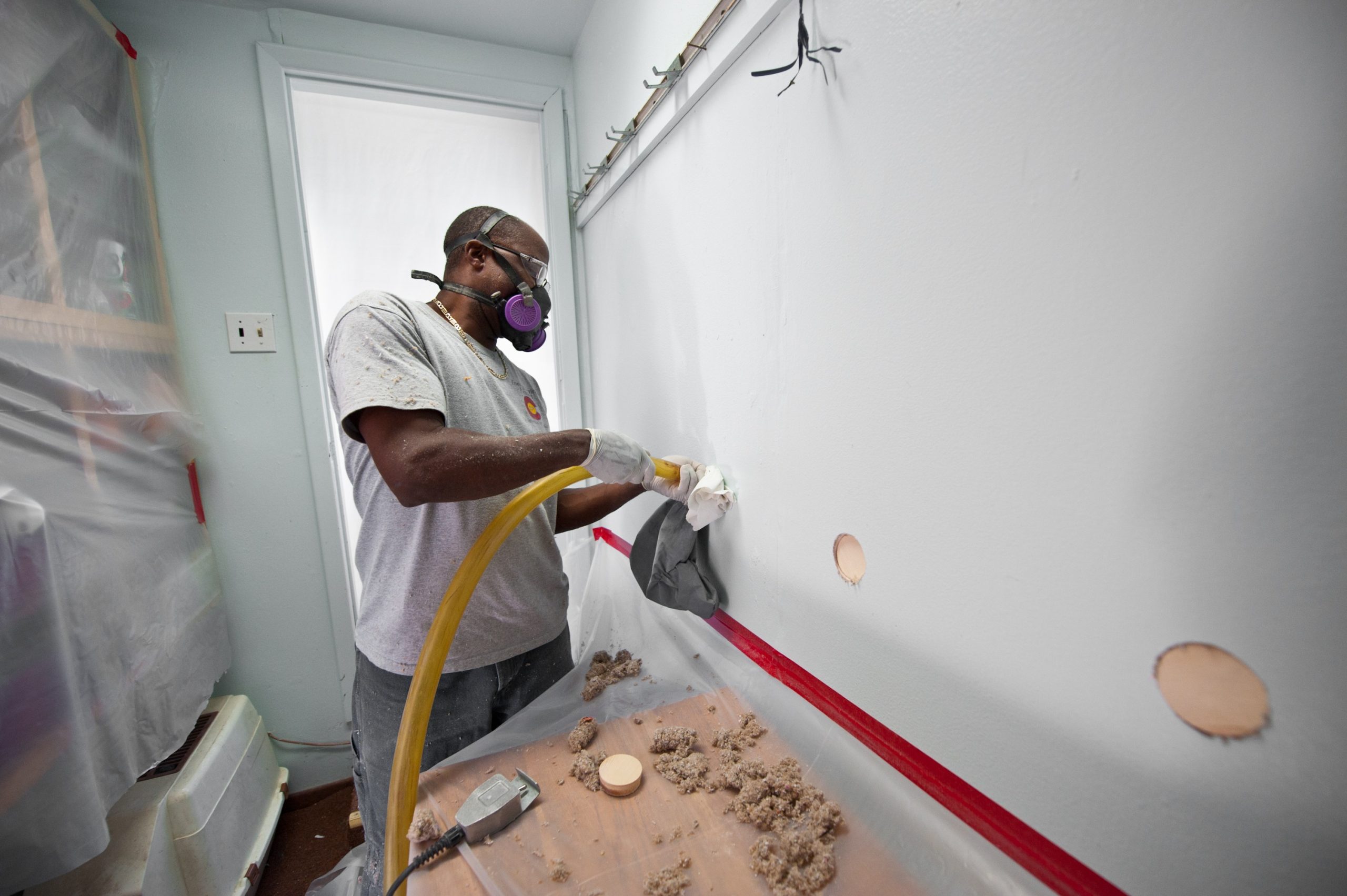 A worker blows cellulose insulation in the interior walls of a home.