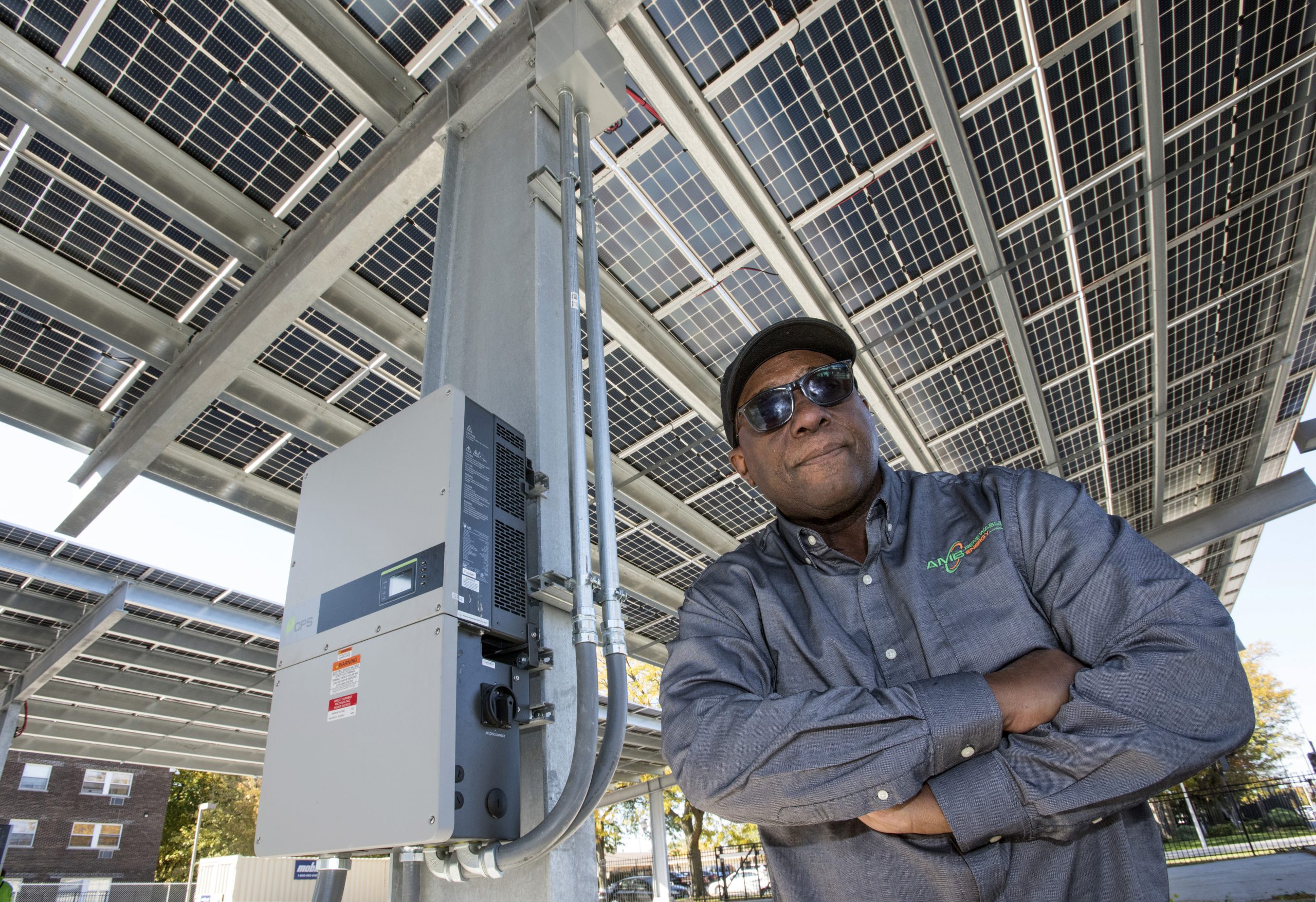 Arthur Burton poses with solar panels and electric vehicle charging stations in the Urban League parking lot.