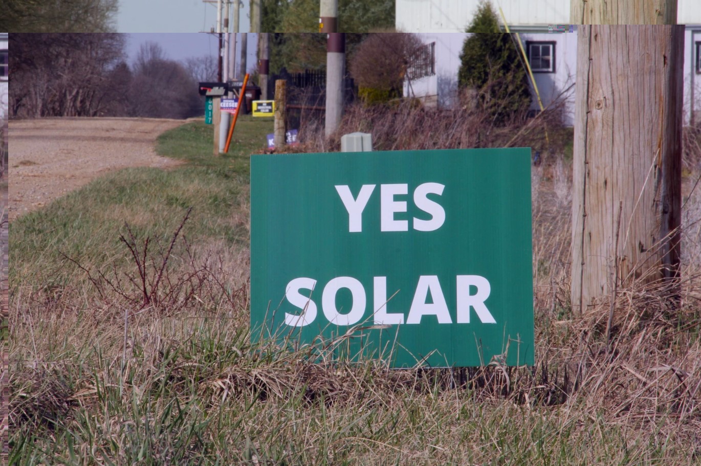 A green sign yard sign with the words "Yes Solar" on a rural road in Knox County, Ohio.